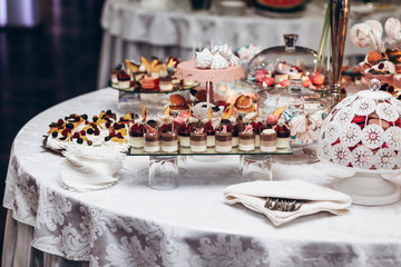delicious candy bar at luxury  wedding reception. exclusive expensive catering. table with modern desserts, cupcakes, sweets with fruits. space for text. baby or bridal shower. holiday celebration