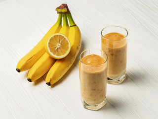Banana smoothie in a glasses and a bunch of bananas with lemon