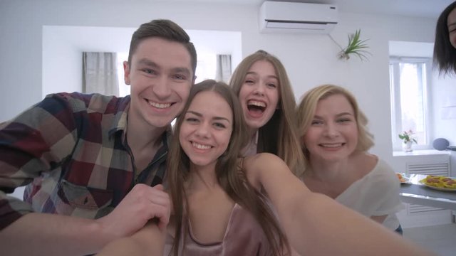 selfie friends, pretty girl holding smartphone and takes photos with funny faces on home party