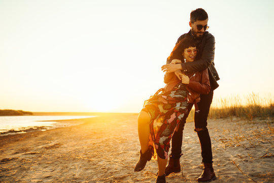 Enjoying time together.  Stylish and loving couple enjoying each other by the sea. The couple is young and in love. The concept of youth, love and lifestyle. Beautiful sunset on a summer day.