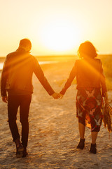 Enjoying time together.  Stylish and loving couple enjoying each other by the sea. The couple is young and in love. The concept of youth, love and lifestyle. Beautiful sunset on a summer day.