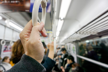 Closeup hand of human holding handle loop in a subway morning and blurry background.