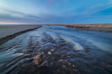 Wide and shallow stream on the shore of the Baltic sea at sunset