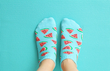 Female feet in colorful socks in watermelon print on a pastel mint background. Top view.Copy space.