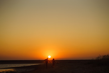 Fototapeta premium Enjoying time together. Stylish and loving couple enjoying each other by the sea. The couple is young and in love. The concept of youth, love and lifestyle. Beautiful sunset on a summer day.