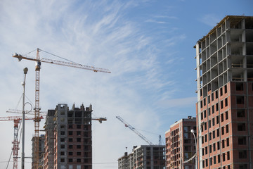 Construction of a multi-storey residential complex. Crane near the building under construction. Background construction site.