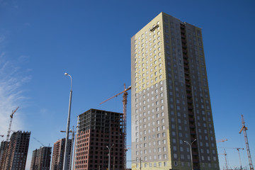 Fototapeta premium Construction of a multi-storey residential complex. Crane near the building under construction. Background construction site.