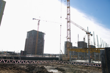 Fototapeta na wymiar Construction of a multi-storey residential complex. Crane near the building under construction. Background construction site.