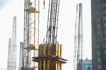Obraz premium Concrete pillars on construction site. Building of skyscraper with crane, tools and reinforced steel bars.