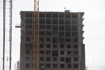 Fototapeta na wymiar Construction of a multi-storey residential complex. Crane near the building under construction. Background construction site.