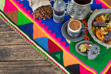 Coffee in the authentic cup and water on the handmade carpet with dry fruits