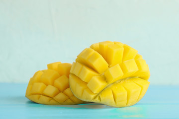Cut ripe mangoes on color table against white background, closeup