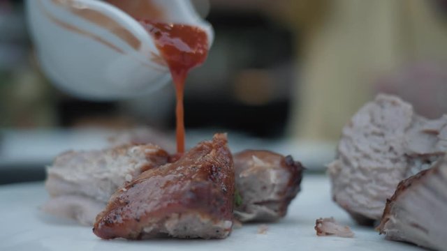 Closeup of grilled meat, skewers with various sauces. Cutting meat with a knife and fork