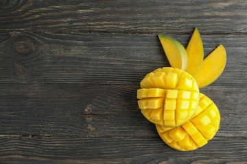 Cut ripe mangoes and space for text on wooden background, top view