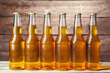 Fresh beer in glass bottles on wooden background