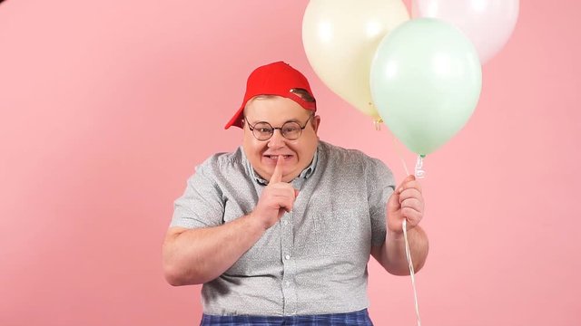 Plump softie man much similar to Winnie the Pooh asks to keep secret that he has air baloons on the birthday of his daughter, keeps finger near his lips.