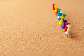 Group of thumbtacks pinned on corkboard