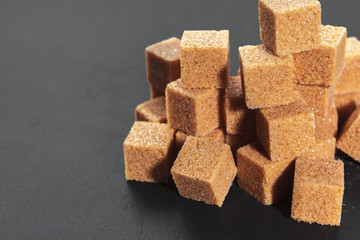 Natural brown sugar cubes on rough black background