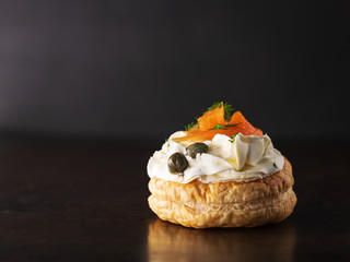 Smoked salmon tartlets snacks with cream cheese on a dark background with copy space.
