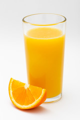 a glass of orange juice and a slice of orange on a white background