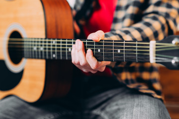 Fototapeta premium Guitar player. Selective focus of male fingers touching strings while playing the guitar