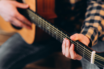 Fototapeta premium Guitar player. Selective focus of male fingers touching strings while playing the guitar