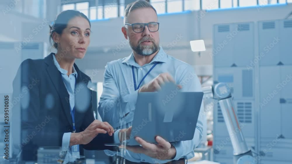 Poster female chief engineer talks with male electronics specialist, explaining things, he holds on laptop 