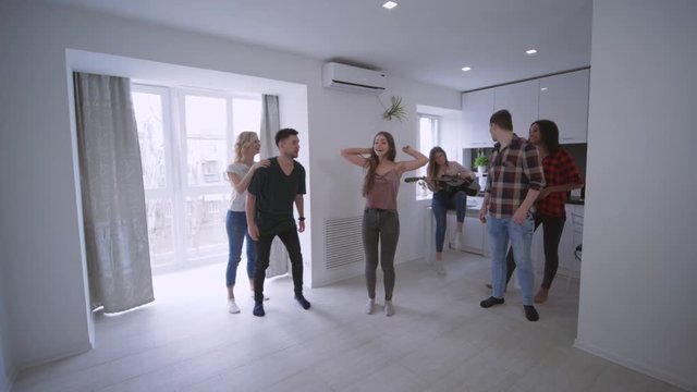 fun loving friends having piggyback races against each other on the apartment at home party in slow motion