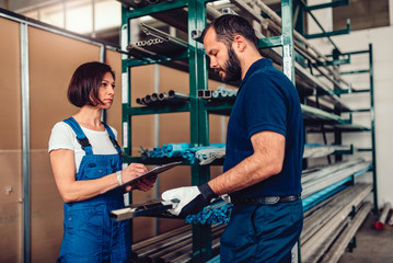 Female stock clerk processing purchase order with warehouse worker