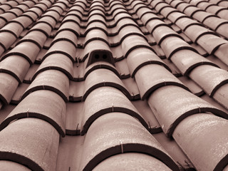 full frame diminishing perspective view of an old roof with curved clay red tiles in lines with ventilation slots