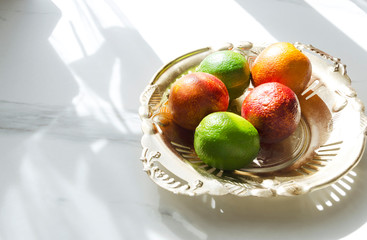 Fresh juicy fruits on the rustic metal tray, white marble table in the kitchen.Morning lights in the kitchen