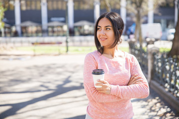 Smiling young woman holding plastic coffee cup outdoors