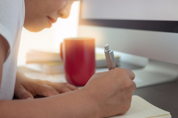 Women working on the desk and desktop computer, notebook, red coffee mug