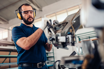 Factory worker operating band saw cutting machine