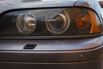 The dirty headlights of a car. Close-up