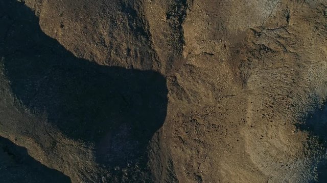 Slow, aerial downward view moving over dry, barren mudstone embankments in a desert