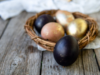 Golden and black eggs in a nest on an old wooden background. Copy space, selective focus, close up. Eggs for Easter. Card.