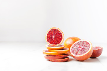 Pile of blood orange slices and halfs of it on the white table.Empty space for your design