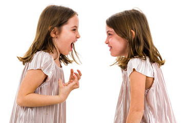 Identical twin girls are looking at each other and smiling.