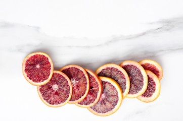 Lot of blood orange slices on the white marble table, top view. Empty space for your text