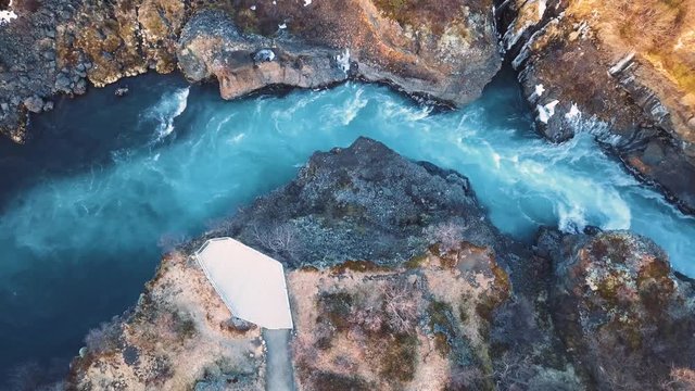 Drone with cinematic movements shows beautiful icelandic waterfall, Hraunfossar, in sunset light from multiple angles.