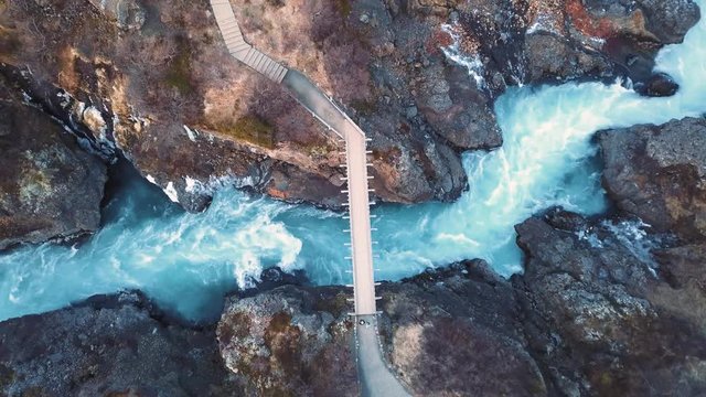 Drone with cinematic movements shows beautiful icelandic waterfall, Hraunfossar, in sunset light from multiple angles.