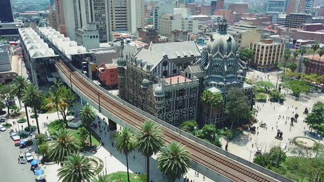 Tilting aerial shot of Medellin city center and Plaza Botero with metro and palms