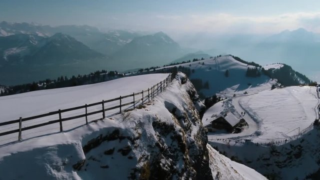 A drone movie along a mountain cliff with a stuning scenic view.
A fence is visible on the edge of the cliff. A fantastic movie on a winterday in the mountains.