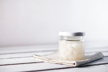 Glass Jar of Pickled Onions on White wood Background