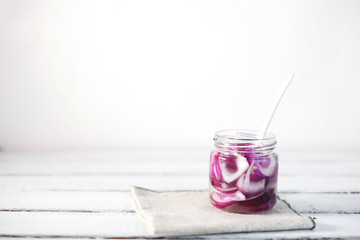 Glass Jar of Pickled Onions on White wood Background