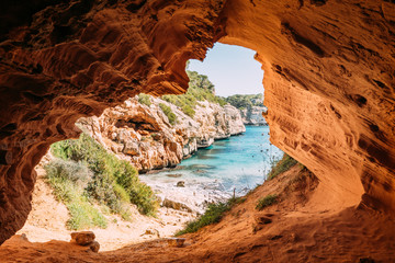 orange leuchtender Sandstein Fels am Höhlen Ausgang an der Cala des Moro auf der Insel Mallorca in...