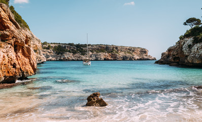 Wunderschöner Strand Cala des Moro ohne Menschen auf Mallorca mit Yacht im Hintergrund