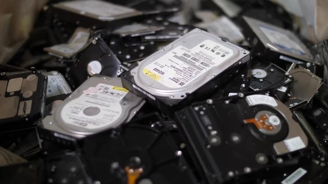 Sorting computer components for recycling, throwing hard discs on stack