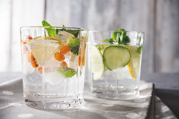 refreshing water with lemon, lime, mint, sea buckthorn, cucumber on grey wooden background